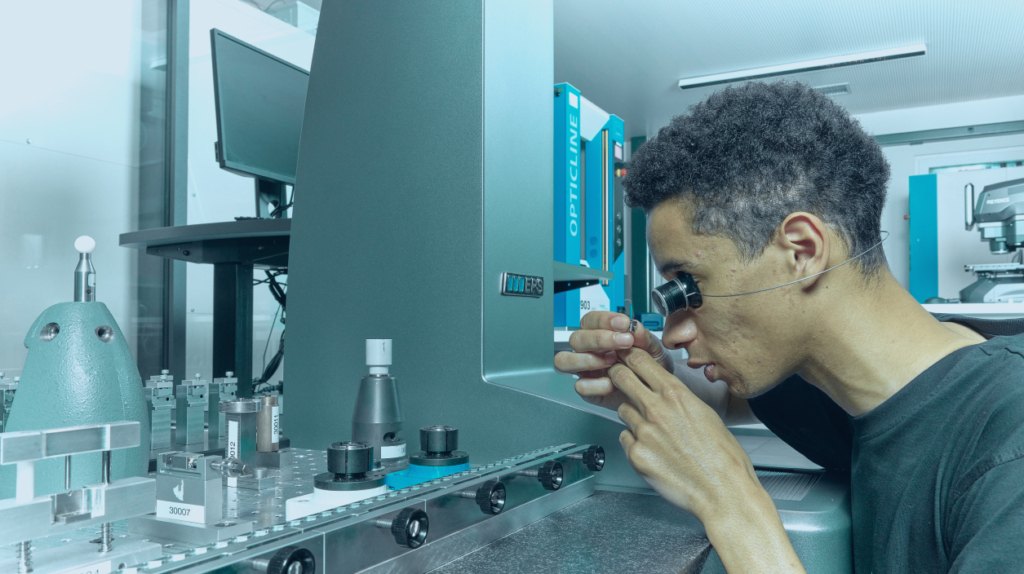 A technician is inspecting micro-mechanical components using magnification tools in a precision lab.