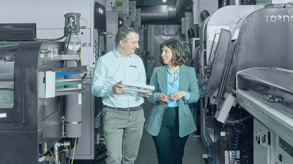 Two professionals discussing a technical component inside a high-tech micromanufacturing facility.