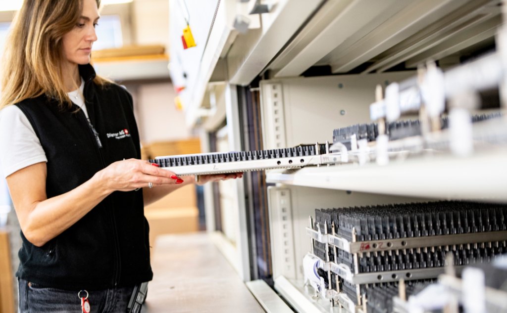 Worker handling organized parts in a storage system within a medical device manufacturing facility, supporting efficient inventory management and shorter lead times.
