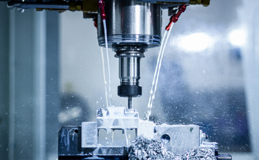CNC milling machine cutting a metal part with coolant spray