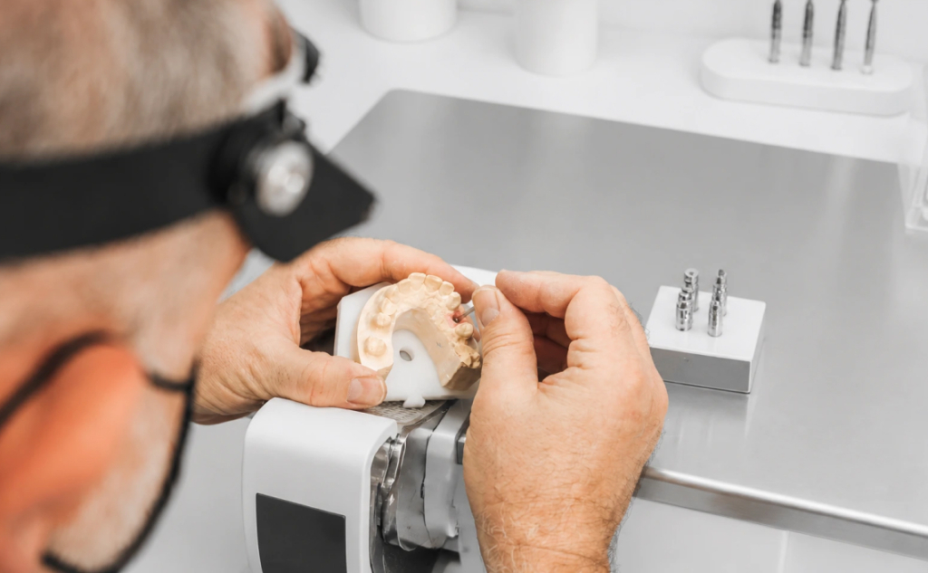 Acrotec Medtech dental technician fitting an implant component onto a dental model